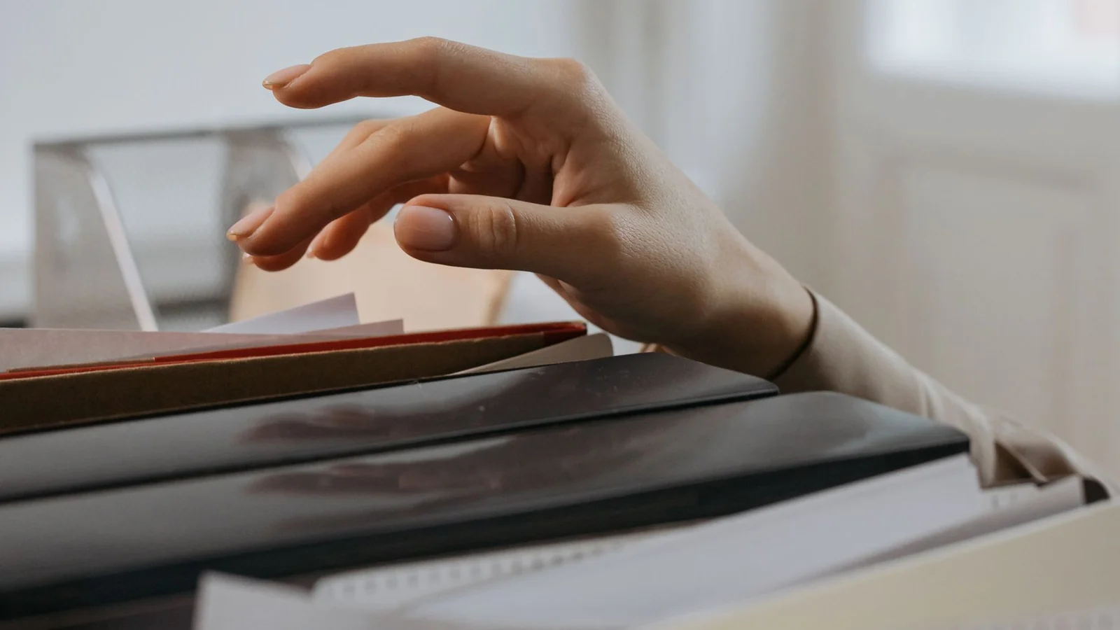 A hand selecting a folder from an organized document drawer.